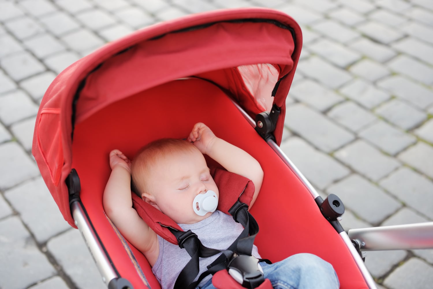 Parent portant un jeune bébé face à lui dans un porte-bébé ergonomique, avec la tête et le visage de l’enfant bien visibles
