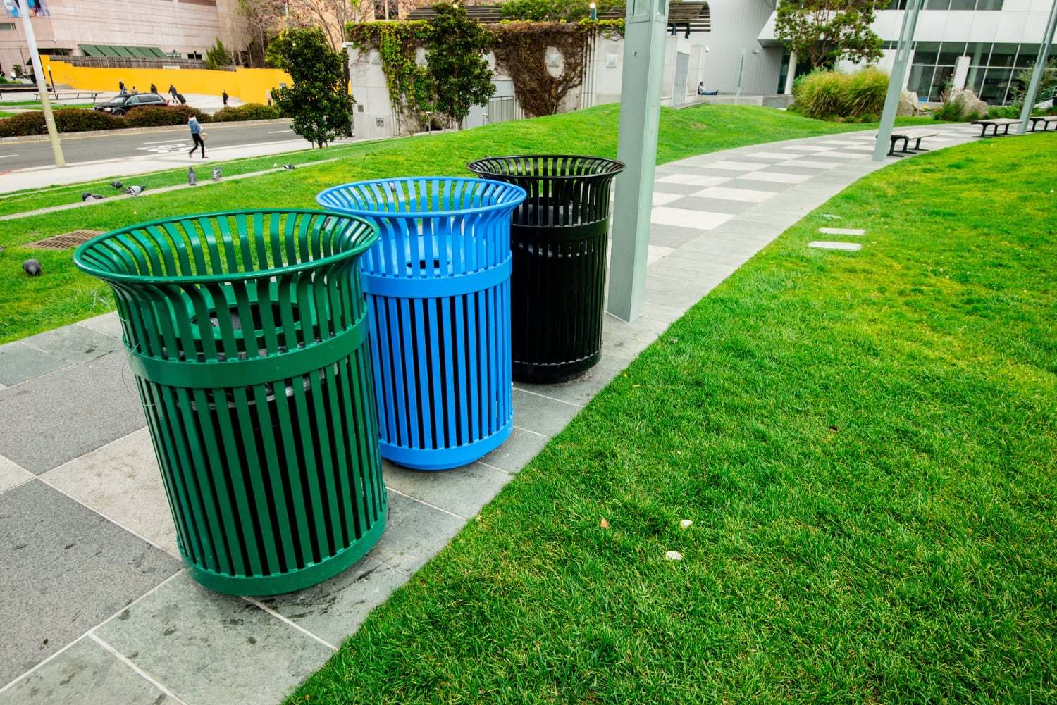 Alignement de corbeilles urbaines contemporaines sur une place publique arborée
