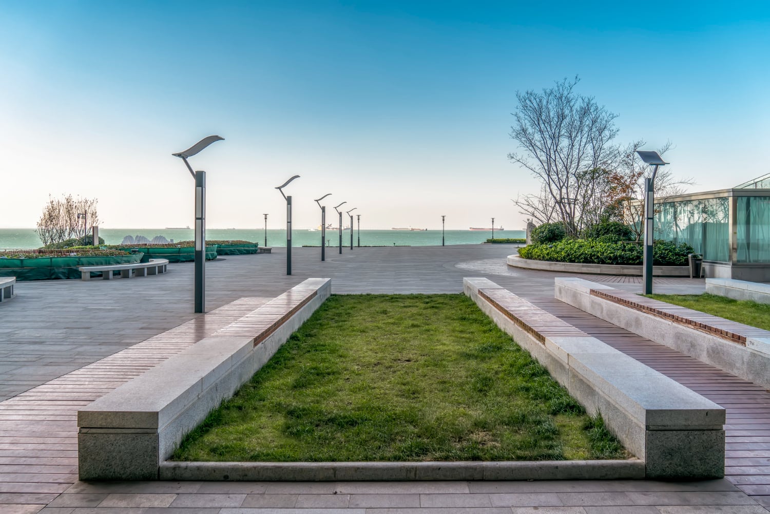 Bancs et jardinières en béton installés sur une place urbaine végétalisée