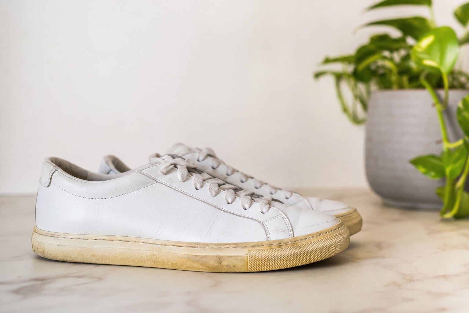 Paire de baskets blanches posée sur une étagère, semelle légèrement jaunie visible en gros plan, lumière naturelle