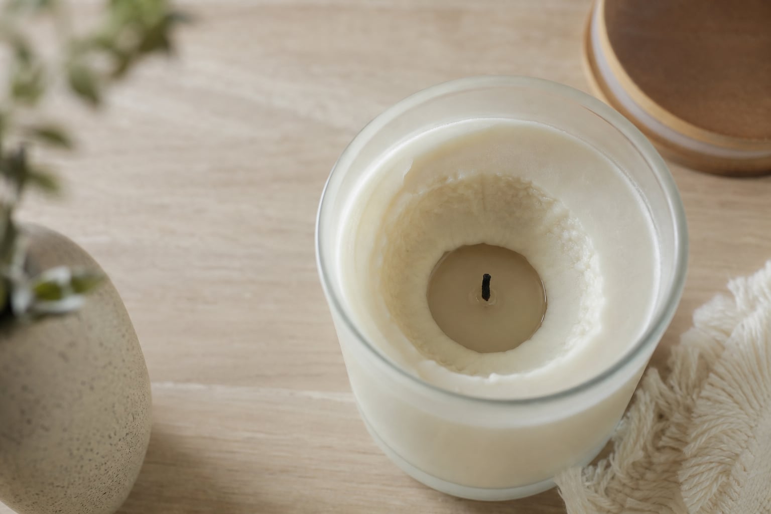 Bougie parfumée dans un pot en verre montrant un puits de cire creusé au centre, cire intacte sur les bords