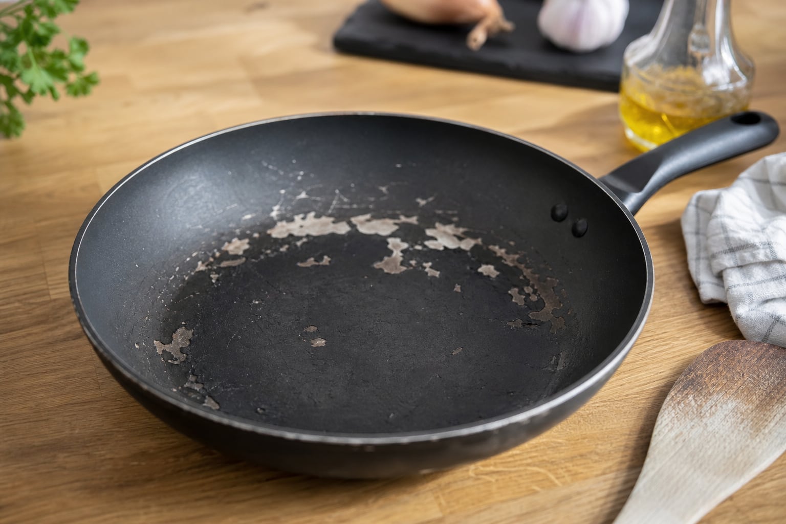 Poêle antiadhésive posée sur une cuisinière, avec des zones ternes et légèrement rayées visibles sur le fond