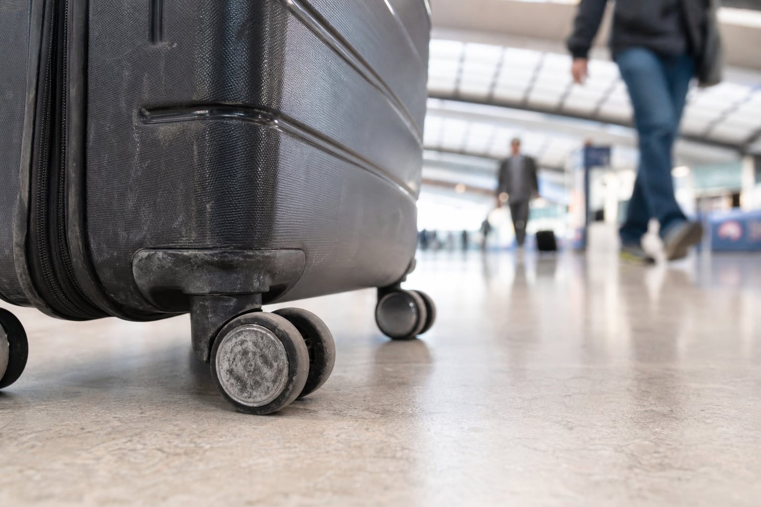 Valise à roulettes tirée sur le sol carrelé d'un hall d'aéroport