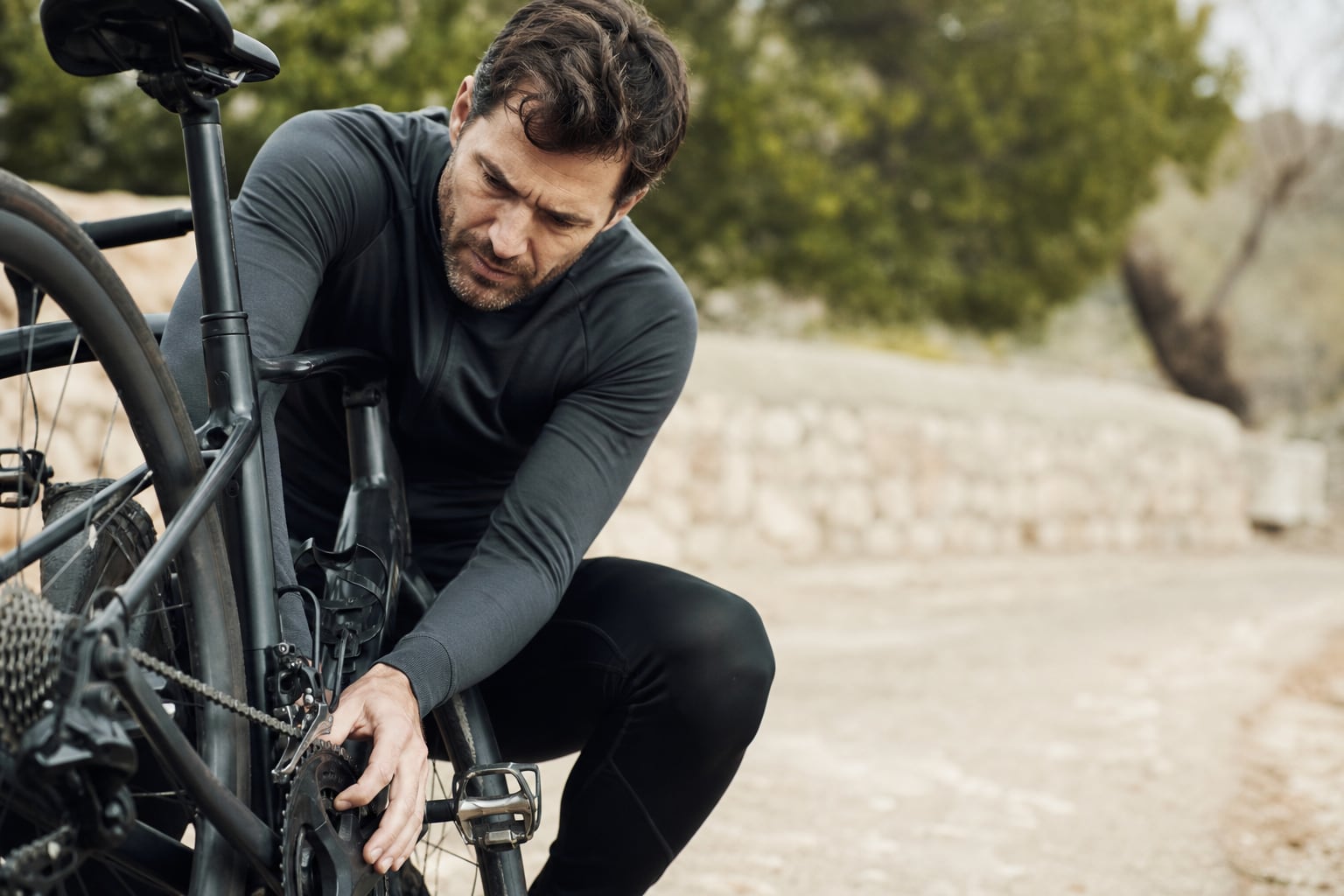 Cycliste vérifiant la chaîne et le pédalier de son vélo dans une cour