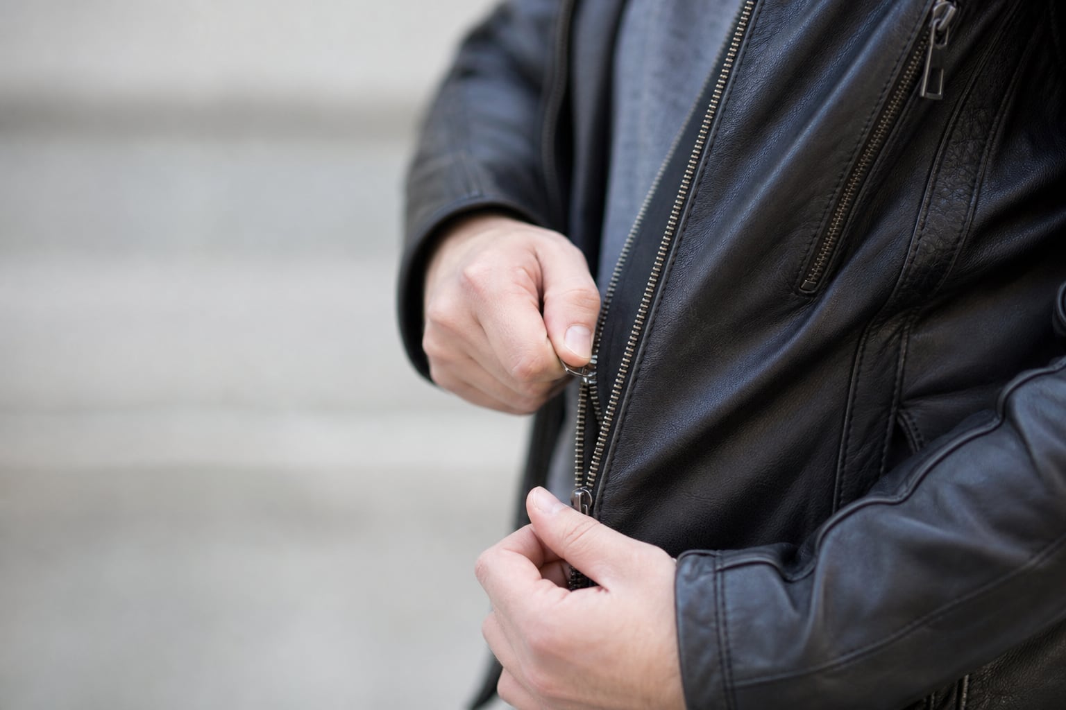 Personne tirant délicatement sur le curseur d'une fermeture éclair de blouson