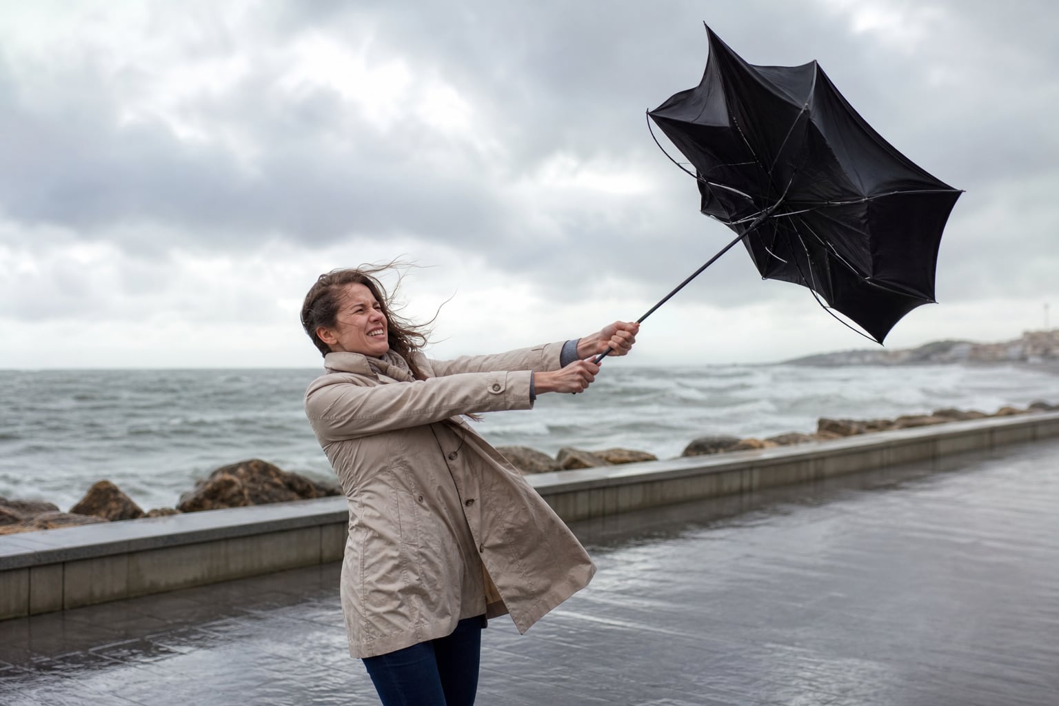 Parapluie noir partiellement retourné par une rafale de vent dans une rue pluvieuse