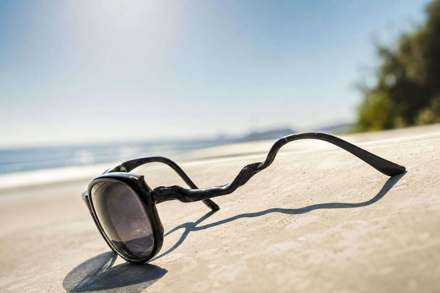 Lunettes de soleil légèrement déformées posées sur un tableau de bord de voiture ensoleillé