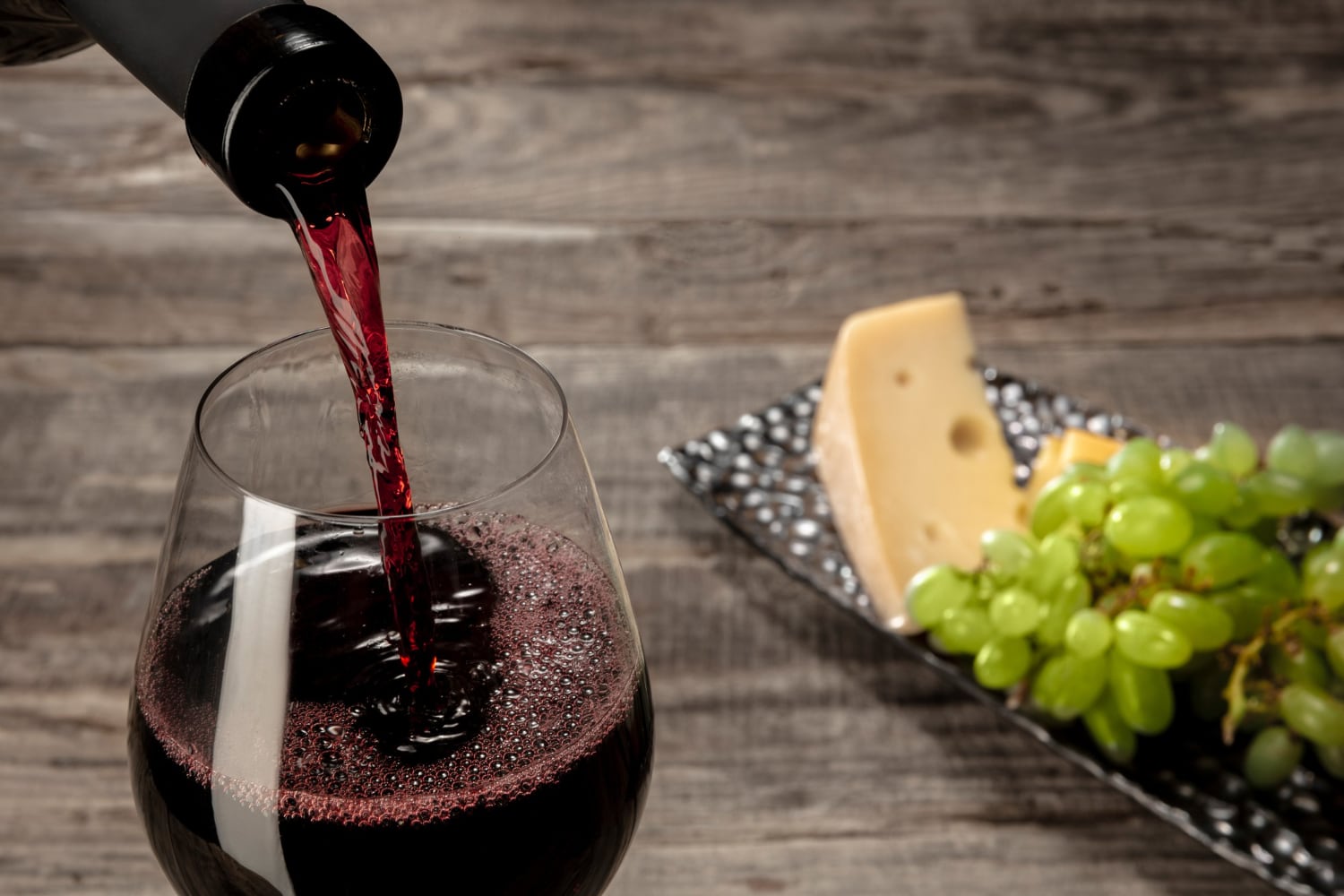 Verre de vin rouge et bouteille sur une table de dégustation, illustrant le sujet des sulfites dans le vin